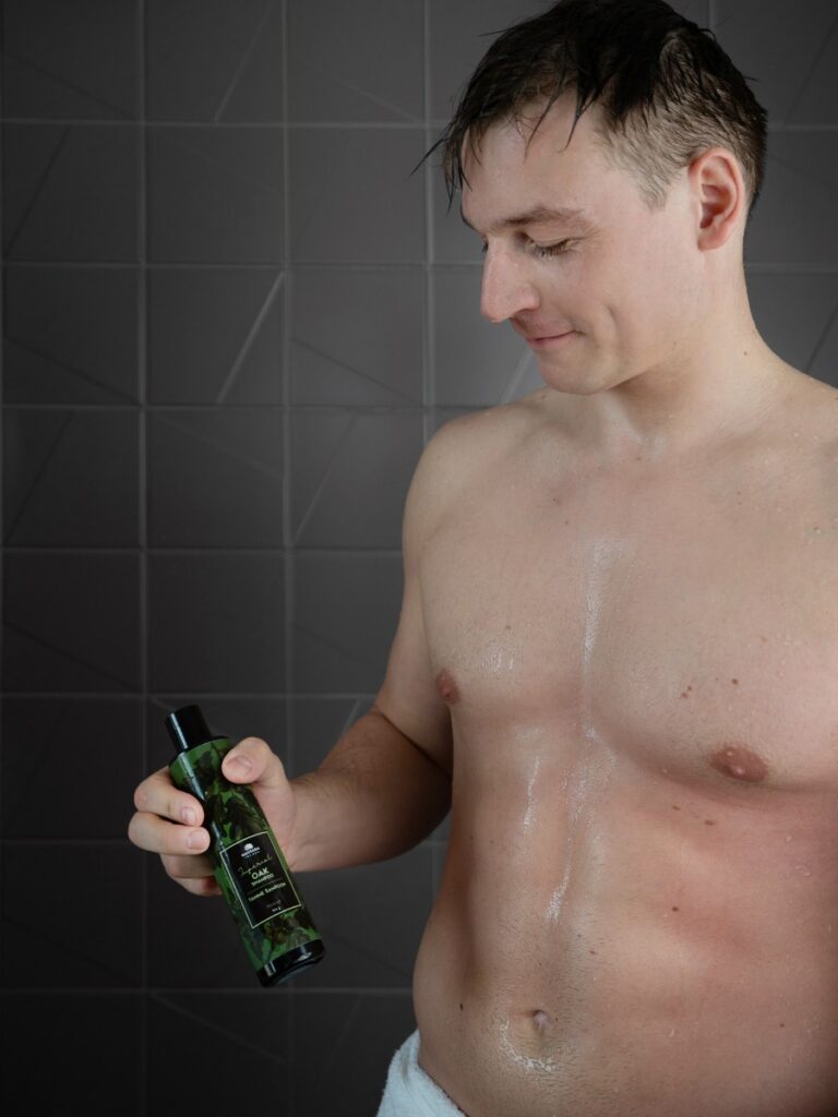 Mann in der Dusche hält Magrada Oak Shampoo – natürliche Haarpflege für Männer