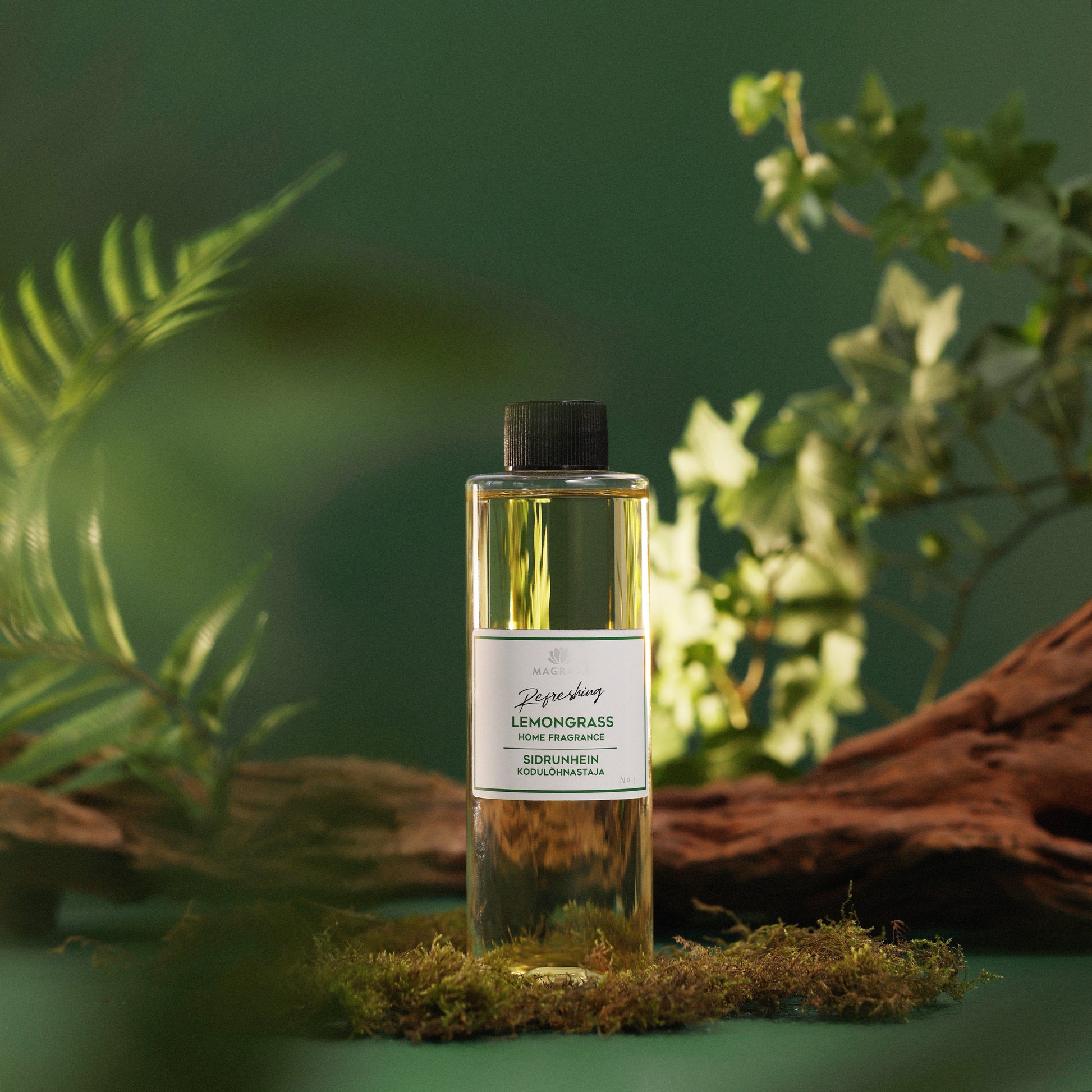 Lemongrass Raumduft-Nachfüllflasche von MAGRADA vor grünem Hintergrund mit Farn und Moos